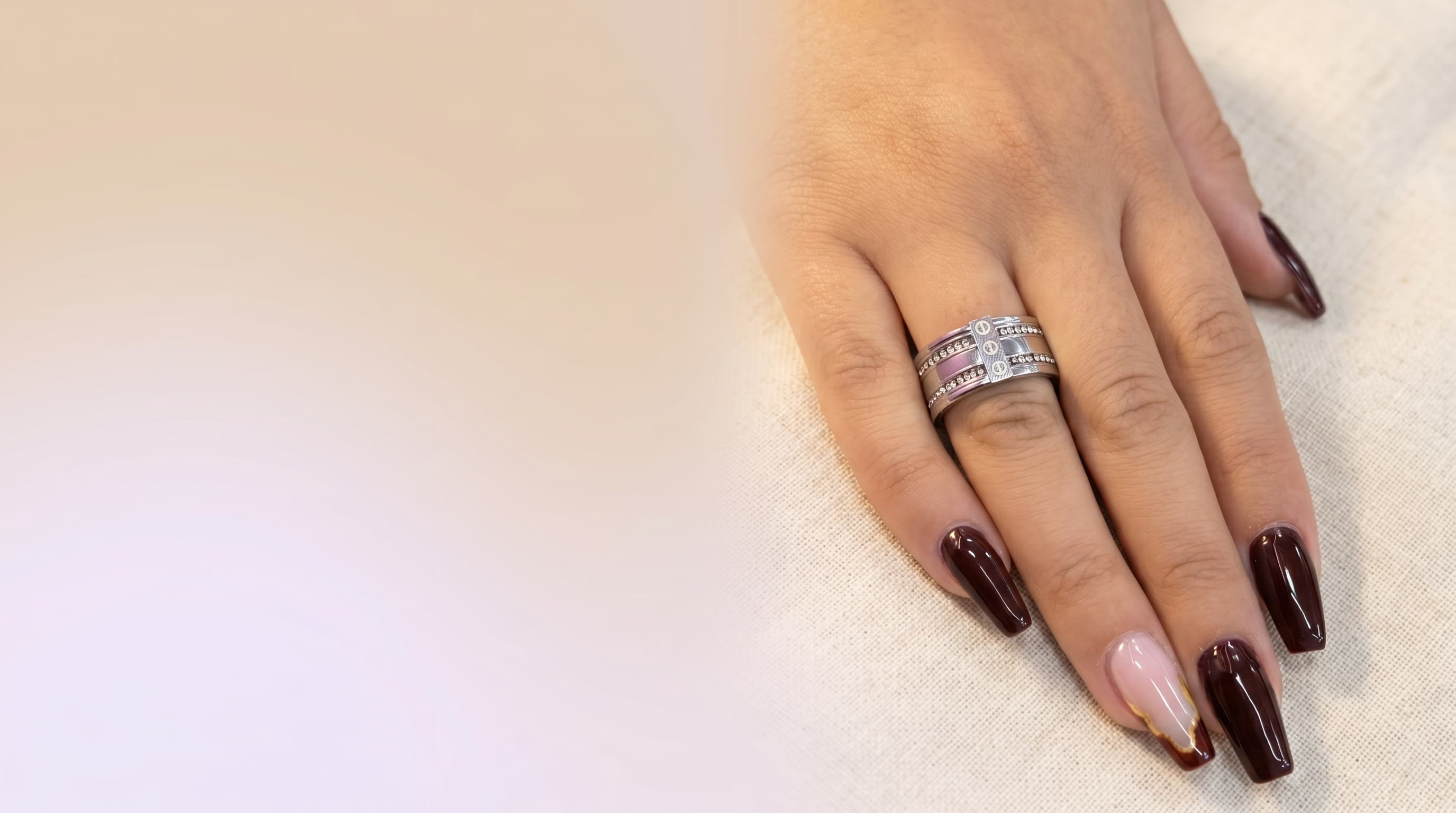 mão feminina usando o Anel Elegance, que possui design triplo com pedras transparentes, sobre um fundo levemente desfocado que realça o brilho da joia.